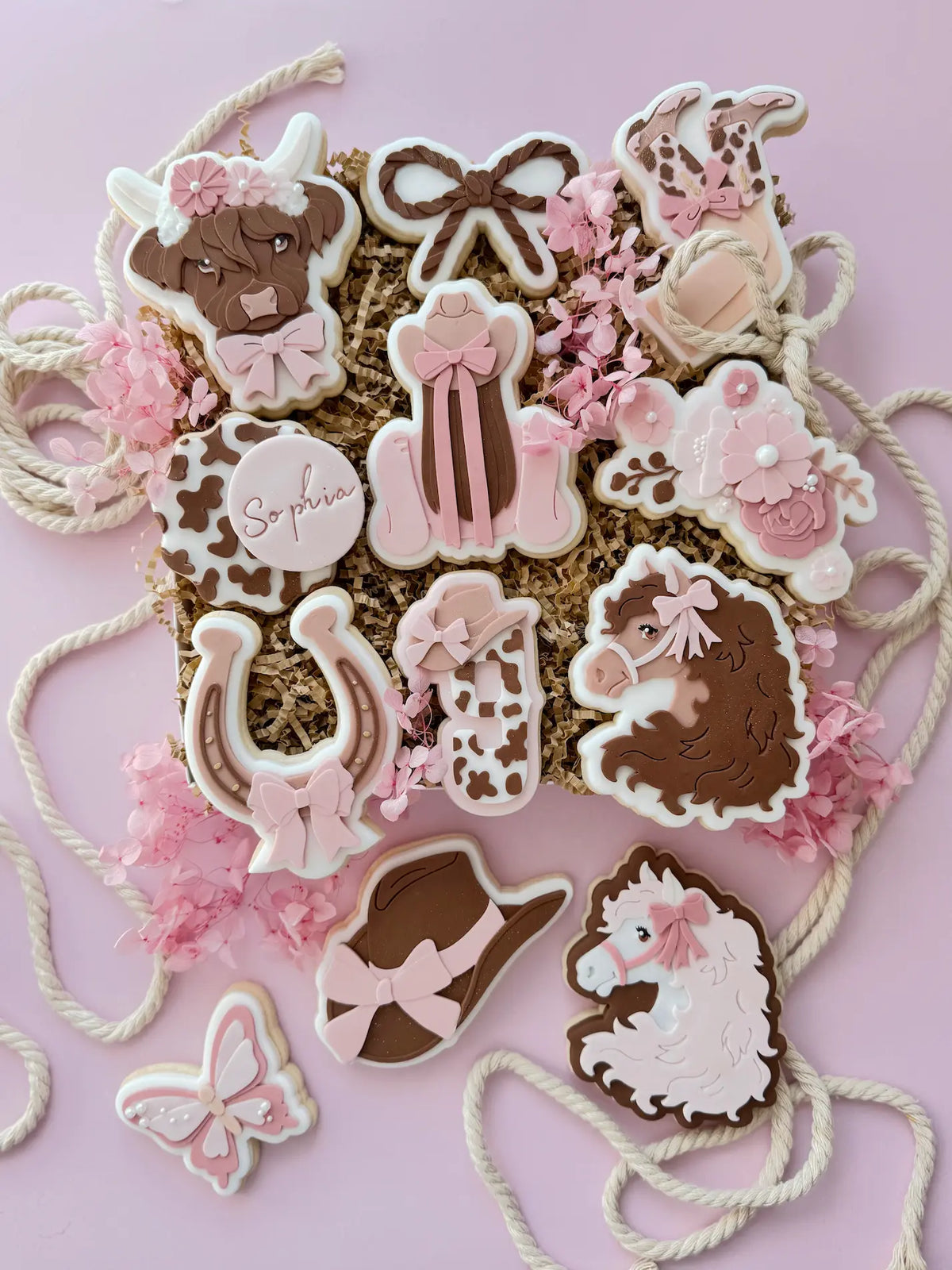 Cowgirl-Keks-Sortiment mit Cowboyhut, Pferd, Highland-Kuh, Hufeisen, Rodeo-Motiven und weiteren Dekorationen als Inspiration.
