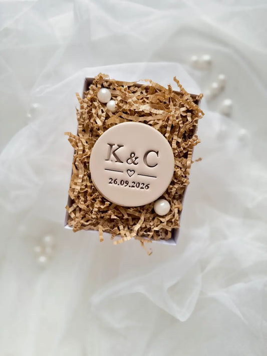 Round decorated cookie with K & C initials, a heart and a date – personalized design example.