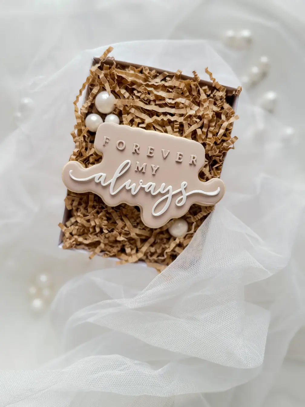 Beigefarbener Keks mit dem Schriftzug Forever my always und weißer geschwungener Schrift.
