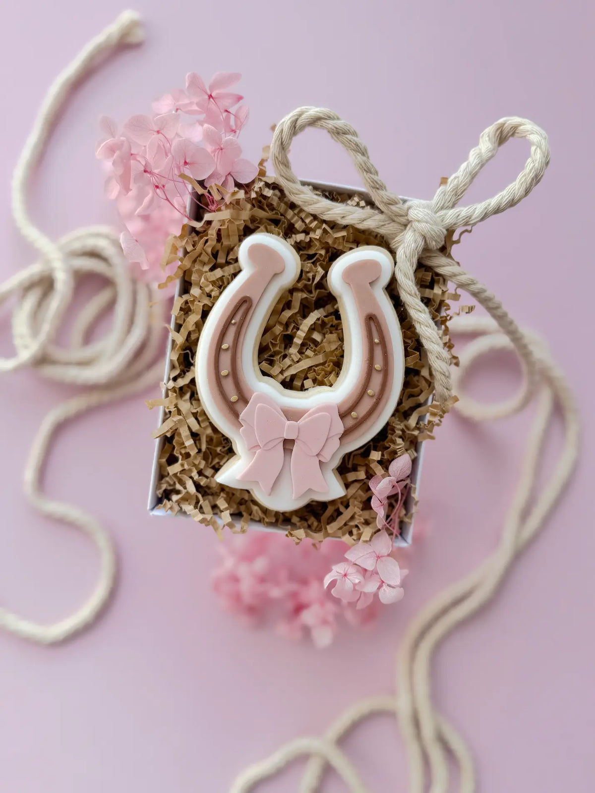 Verzierter Hufeisen-Keks in Rosa und Braun mit rosa Schleife.